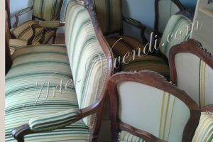 Un canapé et des chaise et fauteuils couvert avec tissu vert jaune beige en rayures avec differents dossiers